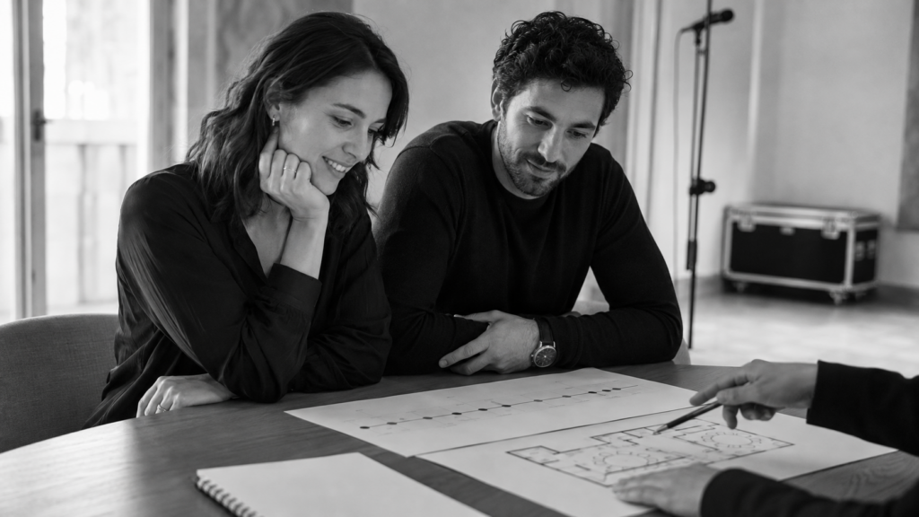 Coppia che valuta il budget musicale del matrimonio attraverso il planning e la piantina della location.